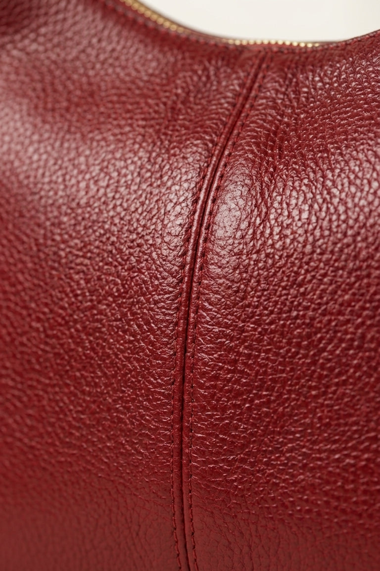Close-up of a red leather handbag with visible texture and stitching.