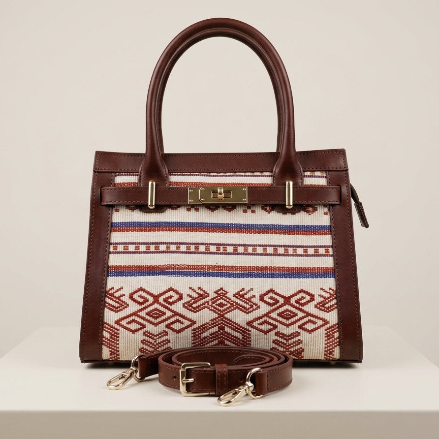 Front view of the Maison Raven Heritage Satchel featuring a centered geometric hand-woven textile pattern, premium dark brown leather trim, and gold-tone hardware on a minimalist studio background.