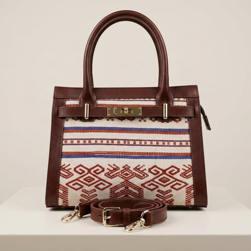 Front view of the Maison Raven Heritage Satchel featuring a centered geometric hand-woven textile pattern, premium dark brown leather trim, and gold-tone hardware on a minimalist studio background.