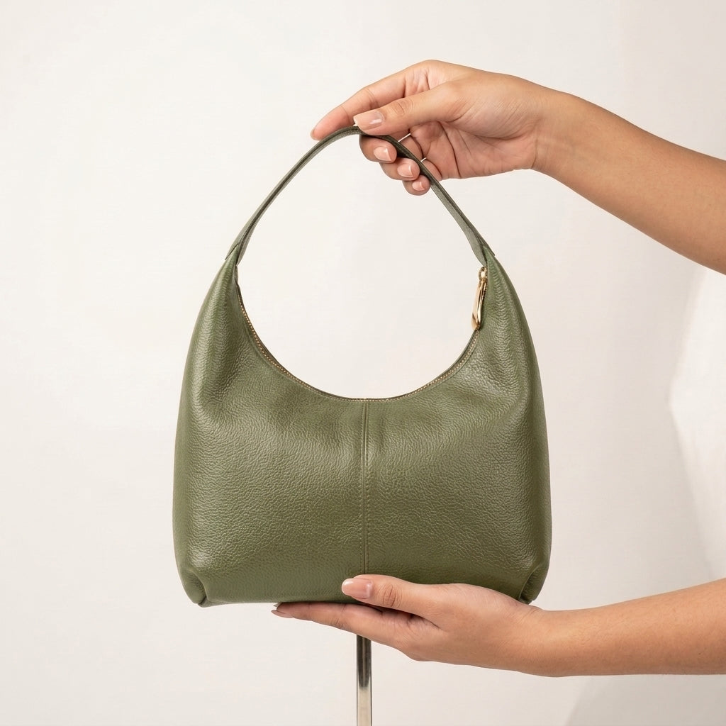 Green handbag held by a person against a white background