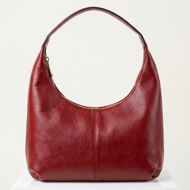 Red leather handbag on a white pedestal with a white background